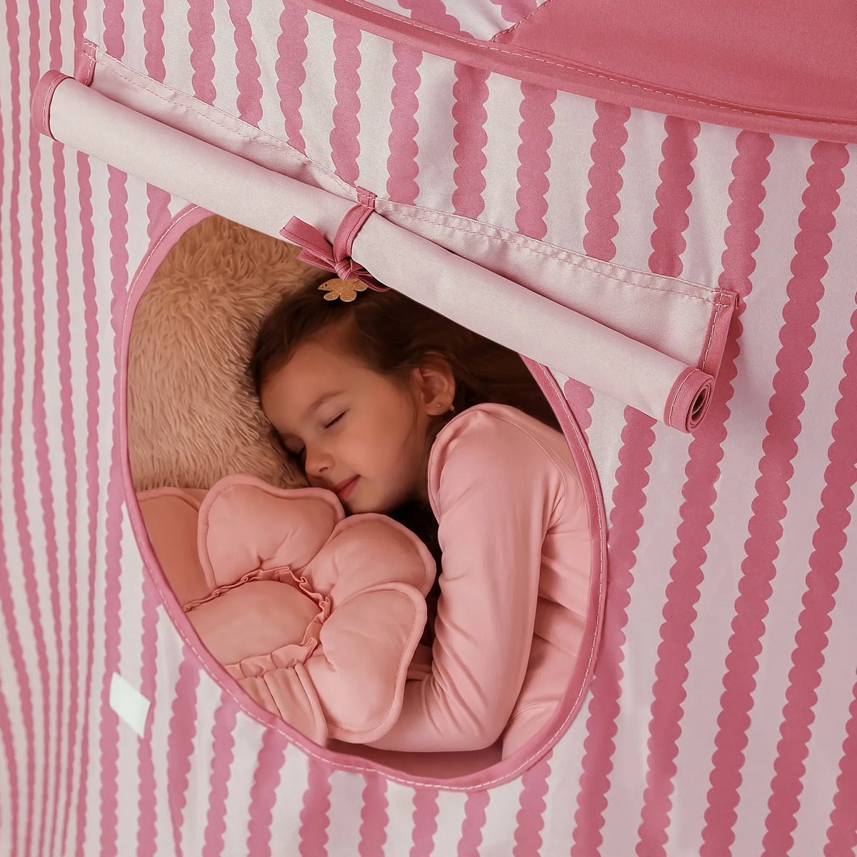 A child sleeps inside a pink-and-white striped Starry Indoor Play Tent for Toddlers, visible through a circular window.