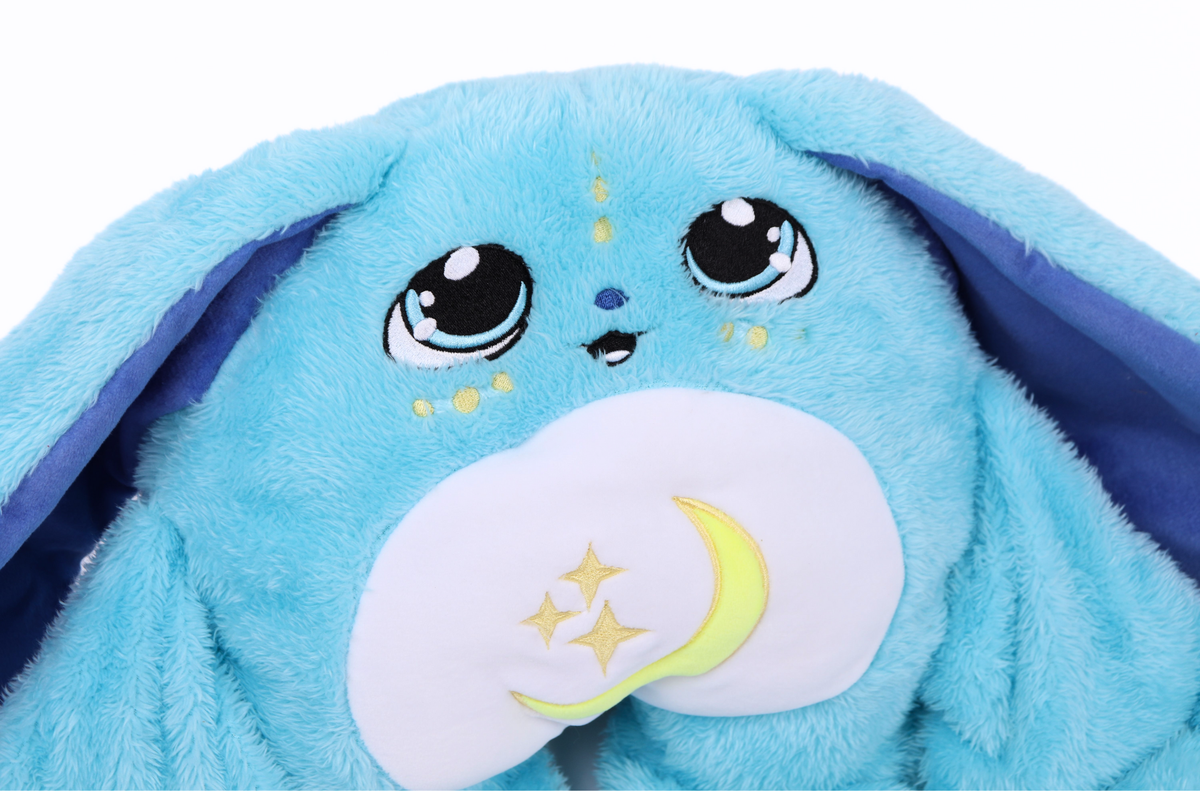 Close-up of a Bo Jr. Moon Pal – 2.5 lb Kids Weighted Plush, a blue weighted stuffed rabbit with large, wide eyes and a white belly patch featuring a crescent moon and stars.