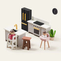 The Tiny Land® Sweetwood Edge Dollhouse kitchen set includes two figures at a table, fridge, stove, sink, wall clock, brown stool, and potted plant—all arranged in a minimalist modern setting.