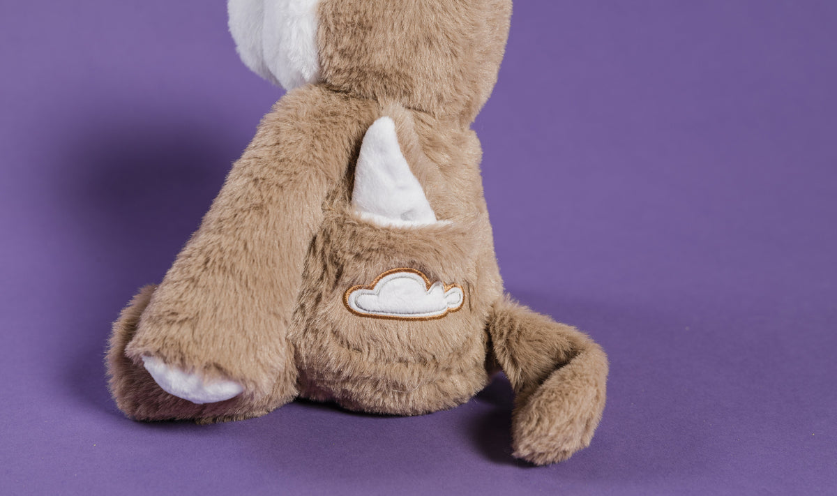 Alfie the Wolf Plush + Book is a tan plush wolf toy sitting with a white cloud patch on its back, designed as a calming toy for children.