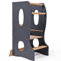 The Stable Montessori Tower: Wooden Growing Chair - Grey is an adjustable learning stool featuring dark blue sides, circular cutouts, two steps, and two safety rails—designed to help children safely reach higher surfaces. This kids kitchen helper perfectly supports your child’s independence in daily activities.