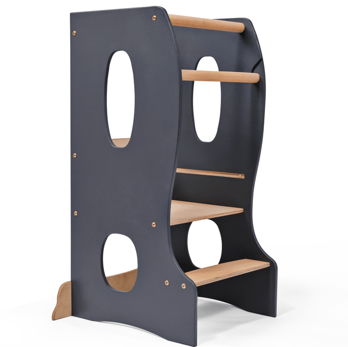 The Stable Montessori Tower: Wooden Growing Chair - Grey is an adjustable learning stool featuring dark blue sides, circular cutouts, two steps, and two safety rails—designed to help children safely reach higher surfaces. This kids kitchen helper perfectly supports your child’s independence in daily activities.