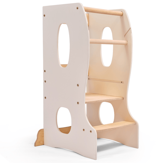 The Stable Montessori Learning Tower: Wooden Growing Chair - Ivory features natural wood, an adjustable platform, two steps, side cut-out handles, and safety rails. Its light ivory design lets kids safely reach higher surfaces while building independence.