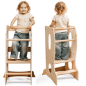 A young child stands on the Stable Montessori Learning Tower: Wooden Growing Chair - Ivory, featuring an adjustable platform, cutout handles, and steps. Shown from front and back, the smiling child wears a beige shirt and blue jeans.