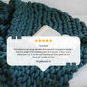 A Knit Weighted Blanket in navy blue is draped on a bed beside an open book. Overlaid is a 5-star review titled I Love It by Stephanie S., praising the blankets weight, comfort, and warmth.