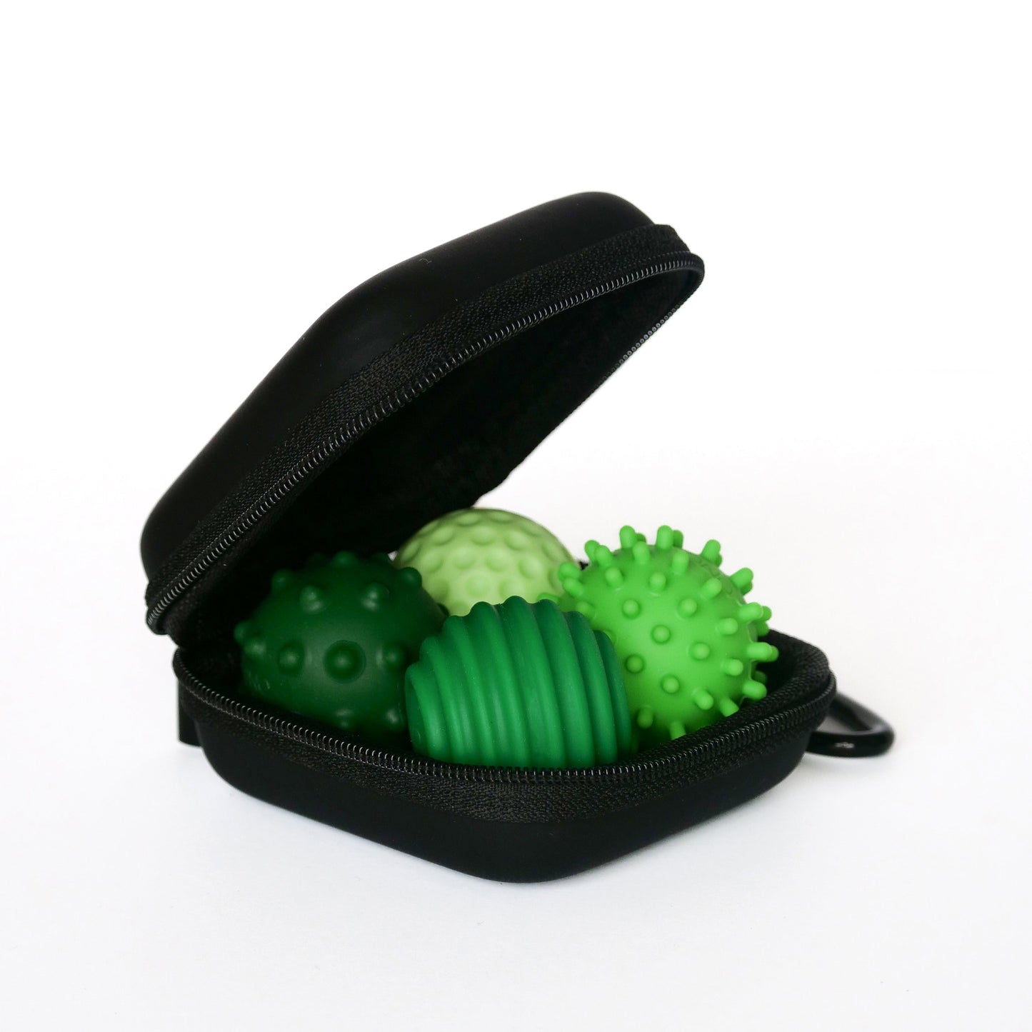A small black zippered case, open to display four emerald Signets—green textured sensory balls with spiky and ridged surfaces—offers a unique fidgeting experience for enhanced focus, all shown on a white background.
