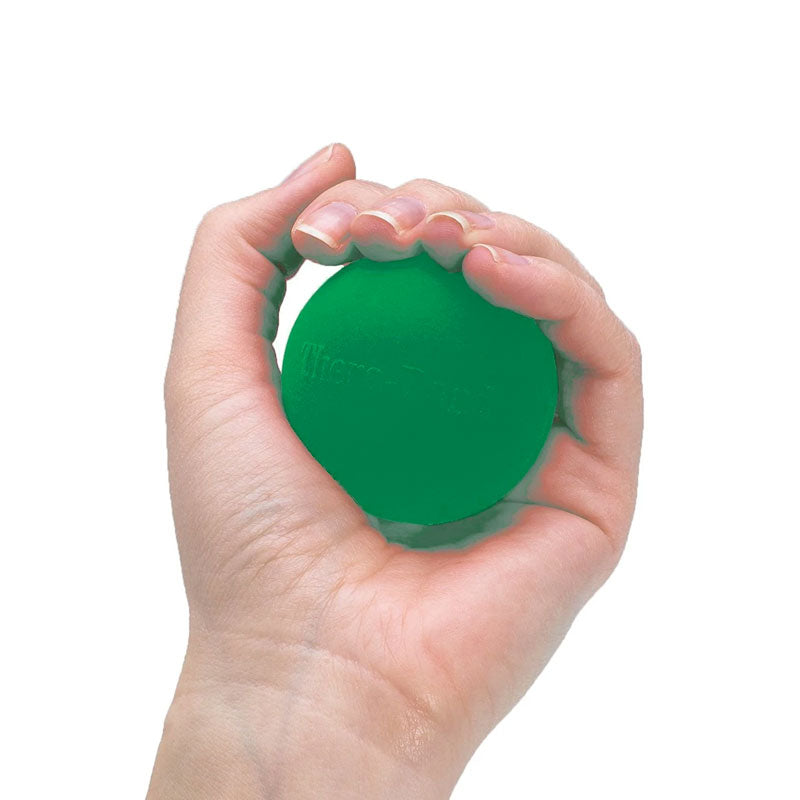 A hand squeezing a round green THERABAND Hand Exerciser Grip Ball to improve grip strength.