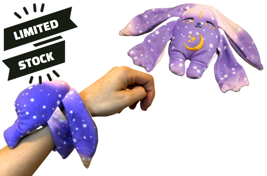 A purple, star-patterned Polli Mini Wrist Hugger – Magnetic Sensory Plush wrapped around a person’s wrist, with a matching plush rabbit floating above next to a Limited Stock banner.