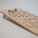 The Oort Cloud – Wooden Marble Run Puzzle featuring an angled board with carved tracks, colorful marbles, and a small wooden figurine at the start of the handmade game.