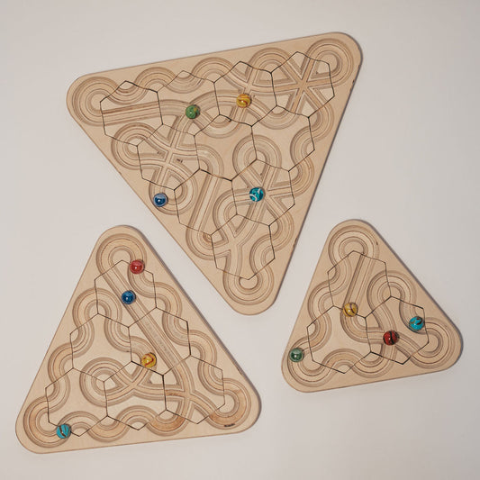 Three triangular The Ouroboros – Wooden Sensory Meditation Maze boards with carved marble maze tracks containing colorful glass marbles.
