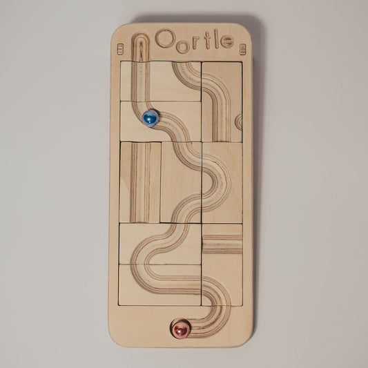 Oortle – Mini Wooden Marble Run Puzzle board featuring an engraved marble run with one blue marble and one red marble.