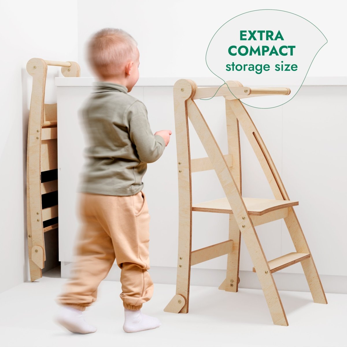 A small child walks near a light wooden Toddler Tower: Foldable Step Stool for Toddlers - Beige with safety rails, while another unit is folded and stored upright. A green bubble reads, Extra compact storage size.