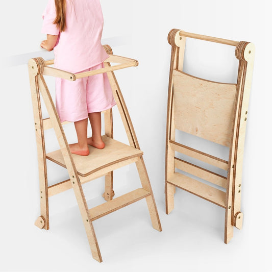 A child in pink clothes stands on the Toddler Tower: Foldable Step Stool for Toddlers - Beige at a counter. Next to it, the same step stool—ideal as a toddler kitchen stool or step stool—is shown folded flat. Both are made of light-colored wood.