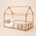 The Twin Size Montessori House Bed for Kids with Fence is crafted from solid beech wood and features a low house-shaped twin bed frame. It comes with a mattress, white and beige bedding, and decorative throw pillows, set against a plain beige background.