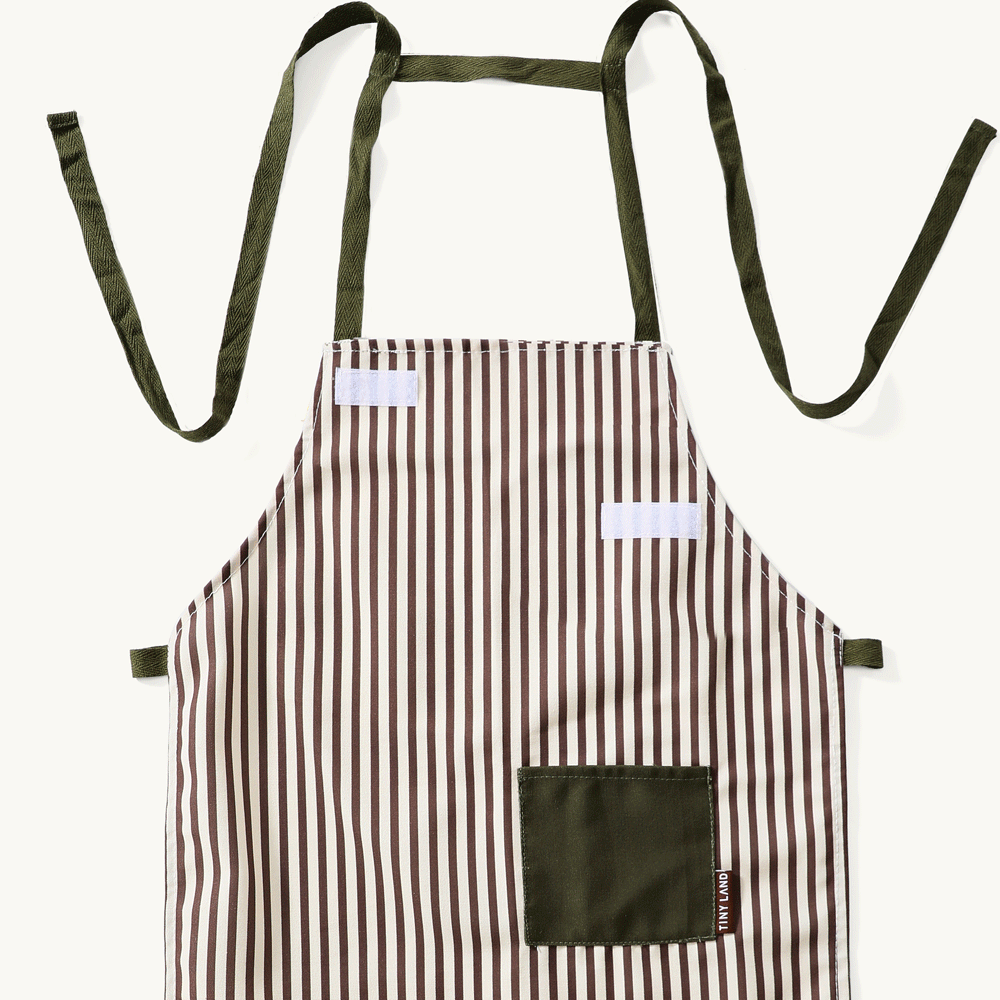 Brown and white striped child’s apron for the BistroSwitch 2-in-1 Play Kitchen & Bistro, featuring dark green straps, a matching pocket, and hook-and-loop fasteners on the chest.