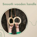 Two children’s hands hold the Wooden gymnastic rings for kids, their smooth wooden handles hanging securely by ropes from a tree. The text Smooth wooden handle appears above the image—an inviting scene that promotes children’s physical development and fitness.